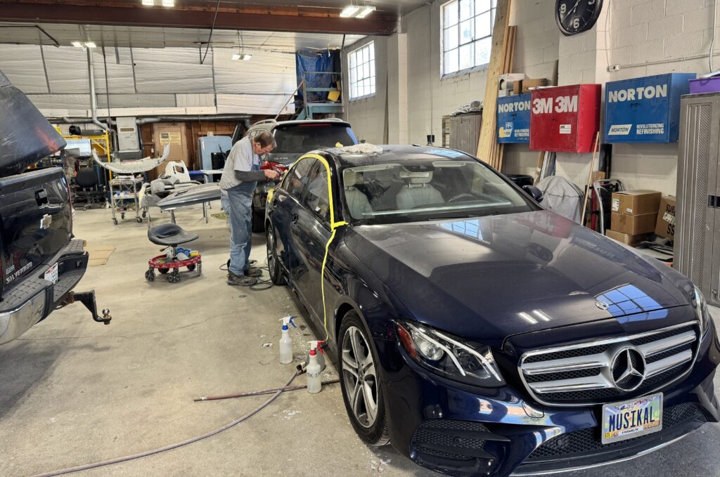 Eurotech Auto Body technician repairing and refinishing a damaged car panel inside the Columbus auto body shop, restoring proper alignment and structural integrity.